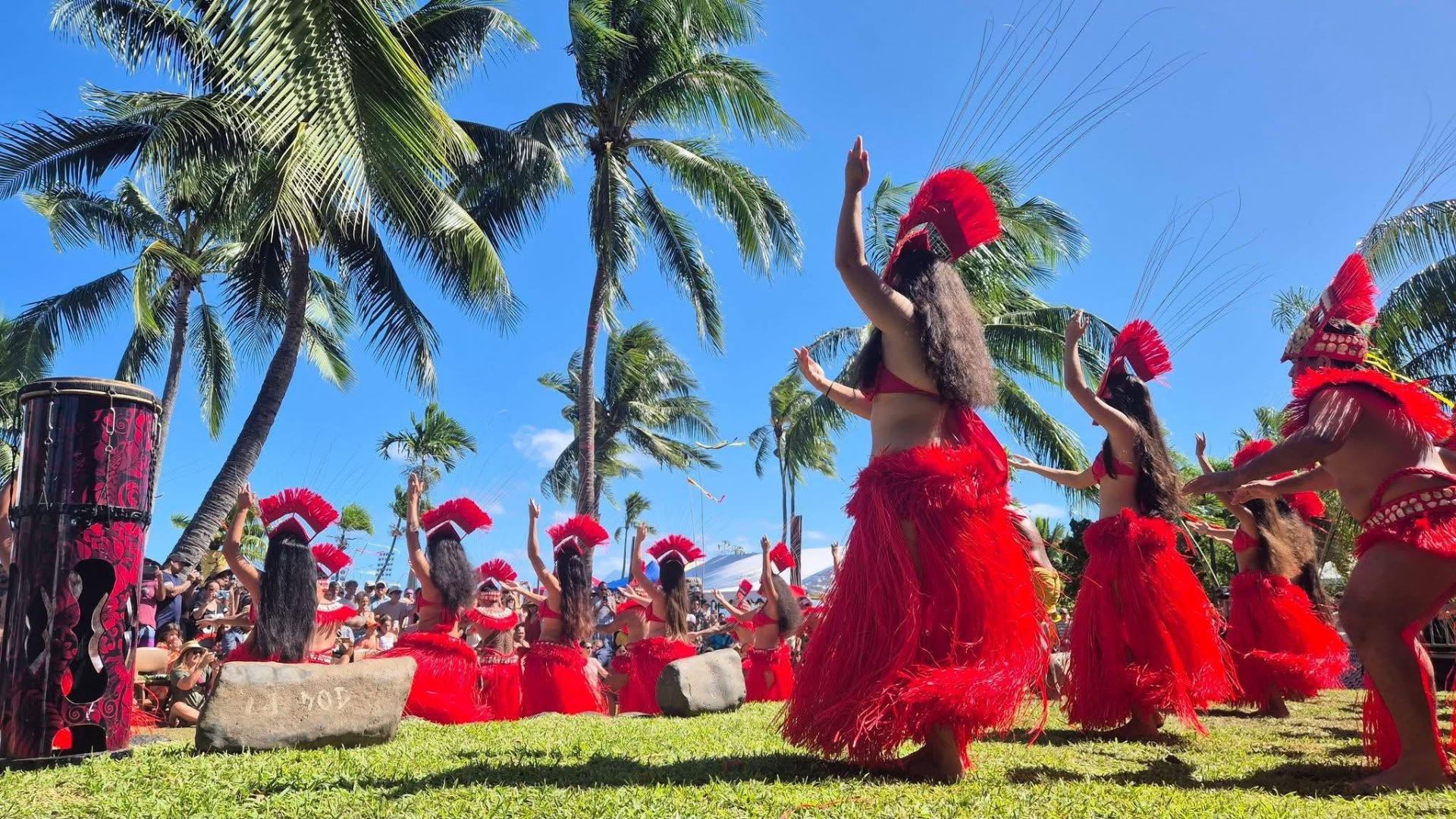 Danseuses en costume rouge sur scène sous les cocotiers
